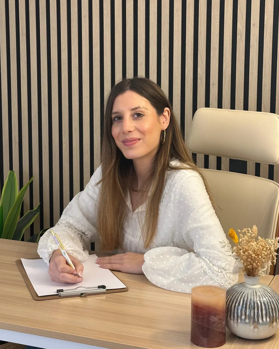 Mar Rodríguez Sánchez, psicóloga, sonríe a cámara sentada a su escritorio mientras toma notas