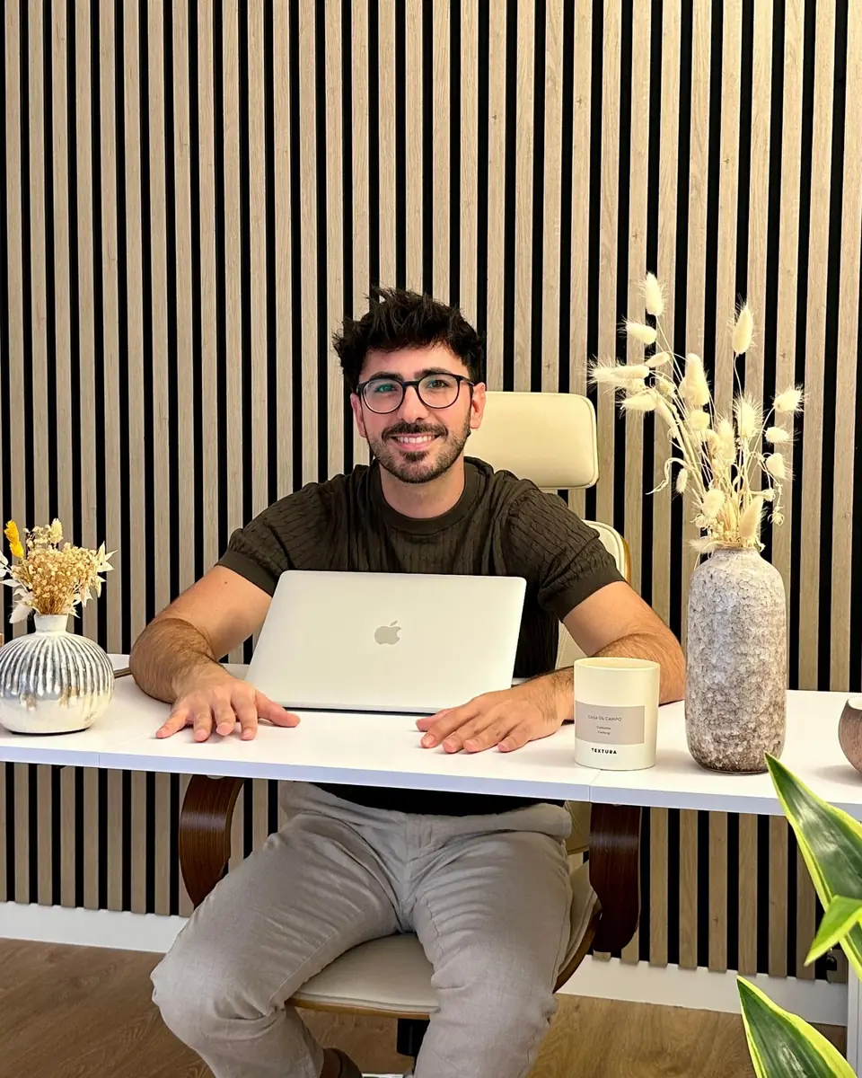 Rubén Lillo, psicólogo, sonríe sentado a su escritorio con el portátil abierto