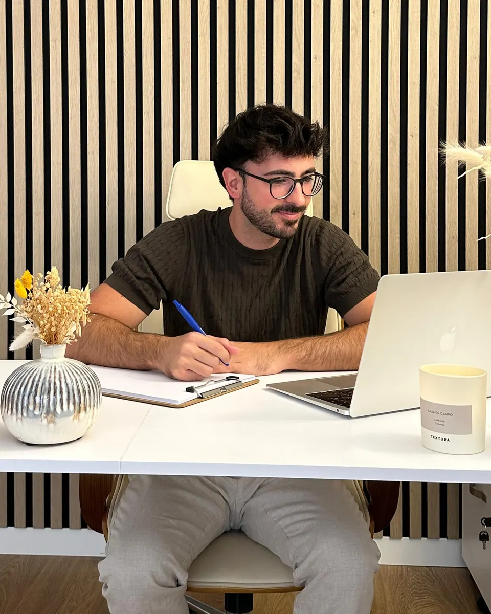 Rubén Lillo, psicólogo y sexólogo, sonríe mientras toma notas junto al portátil en su escritorio